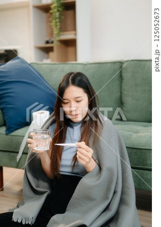 Young Asian woman suffering from flu symptoms, covered with a blanket on a sofa. Concept of illness, healthcare, Young Asian woman suffering from flu symptoms, covered with a blanket on a sofa. Concept of illness, healthcare, 125052673