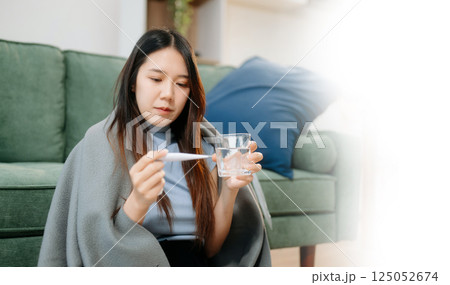 Young Asian woman suffering from flu symptoms, covered with a blanket on a sofa. Concept of illness, healthcare, Young Asian woman suffering from flu symptoms, covered with a blanket on a sofa. Concept of illness, healthcare, 125052674
