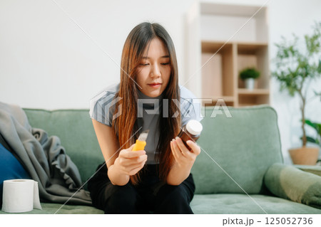 Asian Woman sitting in the sofa with a large number of pills Depressed woman wants to kill herself by drug overdose, depression concept. 125052736