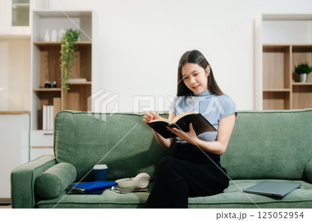 Young asian woman relax on comfortable couch at home texting messaging on smartphone and tablet Young asian woman relax on comfortable couch at home texting messaging on smartphone and tablet 125052954