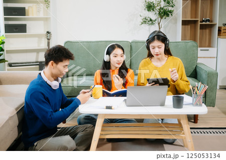 Group of young adults in casual wear, using laptops and headphones, enjoying teamwork, creativity, and learning 125053134