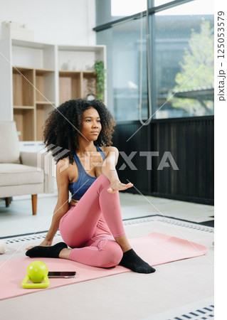 Woman Doing Yoga and Watching Online Tutorials on Laptop, Training in Living Room at home Woman Doing Yoga and Watching Online Tutorials on Laptop, Training in Living Room at home 125053579