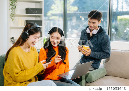 Group of young adults in casual wear, using laptops and headphones, enjoying teamwork, creativity, and learning Group of young adults in casual wear, using laptops and headphones, enjoying teamwork, creativity, and learning 125053648