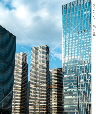 Modern skyscrapers reflect sunlight against a clear blue sky in an urban landscape in a bustling city 125053988