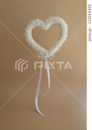 White lilac flowers heart shaped levitate like balloon in pastel backdrop. Symbol of love floral arrangement. Spring concept idea Valentine's Day, weeding proposal postcard copy space 125054489