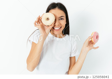 A woman is holding two donuts and smiling 125056041