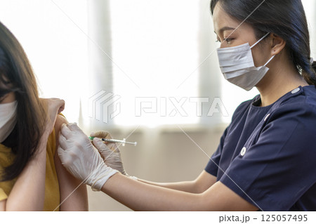 Asian Girl Getting Vaccinated, Receiving Coronavirus Vaccine Injection in clinic. Asian Girl Getting Vaccinated, Receiving Coronavirus Vaccine Injection in clinic. 125057495