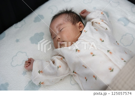 腕を上げて眠っている生後2ヶ月の赤ちゃん 腕を上げて眠っている生後2ヶ月の赤ちゃん 125057574