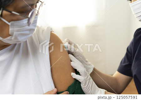 Elderly Asian woman getting coronavirus vaccine by nurse. Medical worker prepare syringe. 125057591