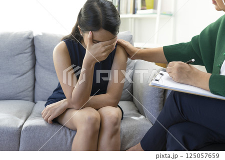 Asian psychologist doctor having session with young depressed woman in clinic. Psychology and mental therapy concept. Asian psychologist doctor having session with young depressed woman in clinic. Psychology and mental therapy concept. 125057659