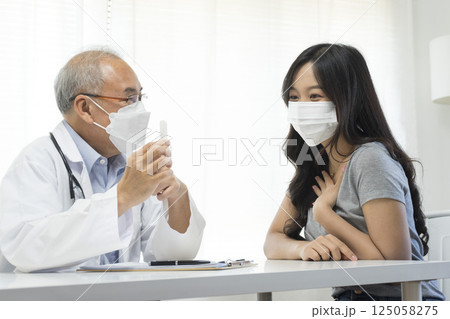 Senior Asian doctor talking with young female patient in hospital. Senior Asian doctor talking with young female patient in hospital. 125058275