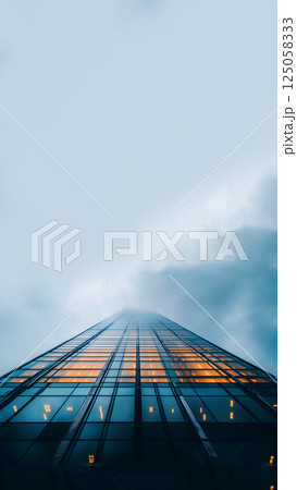 A towering skyscraper disappears into dense fog, creating a dramatic and atmospheric scene. Ideal for reels, stories, and banners with copy space 125058333