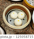 Three mochi balls, in a round container, similar to a steamer cup. 125058715