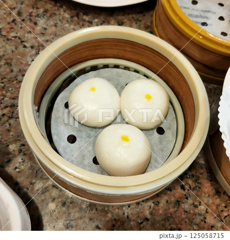 Three mochi balls, in a round container, similar to a steamer cup. 125058715