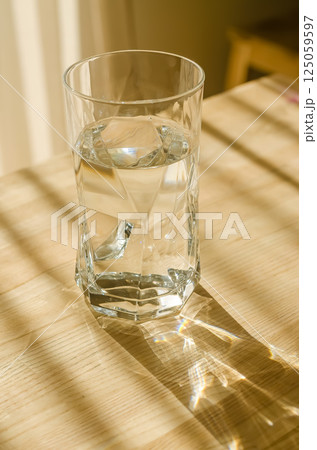 Clear glass of water on wooden table with beautiful sunlight and reflections. High quality photo 125059597
