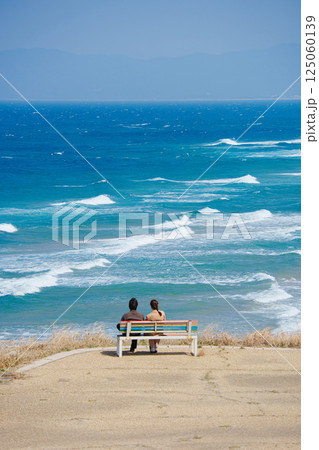 ベンチに座り海を眺めるカップル ベンチに座り海を眺めるカップル 125060139