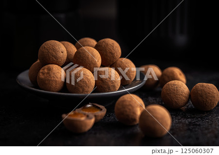 Chocolate truffles with cocoa powder and caramel filling on black table. Chocolate truffles with cocoa powder and caramel filling on black table. 125060307