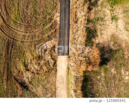Aerial view of a dead-end road surrounded by dry grass and fields 125060341