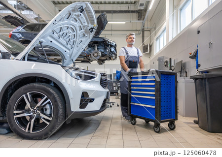 Handyman in auto workshop with equipment for labor work on vehicle repair and diagnostics Handyman in auto workshop with equipment for labor work on vehicle repair and diagnostics 125060478