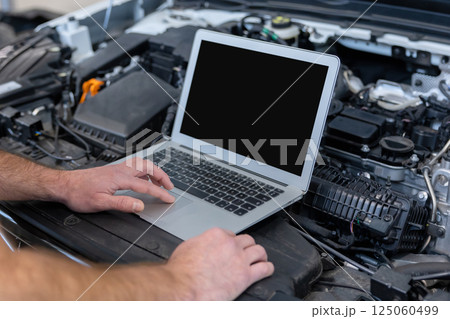 Mechanic man mechanic using laptop computer checking car 125060499