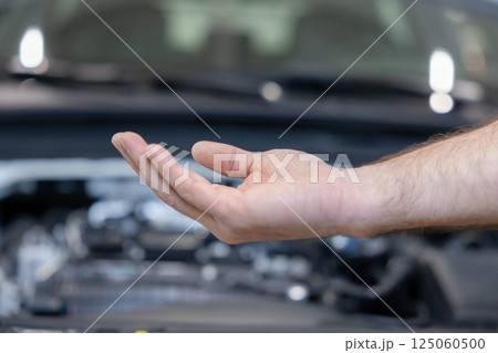 Man master hand ibn front of blur open hood of car Man master hand ibn front of blur open hood of car 125060500