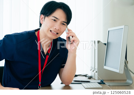 スマホで通話する困った顔の医師 スマホで通話する困った顔の医師 125060528