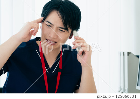 スマホで通話する困った顔の医師 スマホで通話する困った顔の医師 125060531