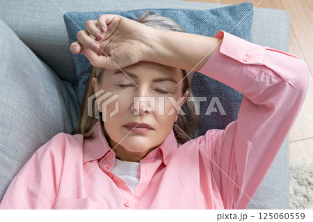 Senior caucasian woman in pink shirt lying on the bed and suffering form the headache 125060559
