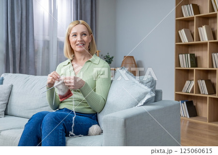 Woman spending time at home and knitting while sitting on the sofa 125060615