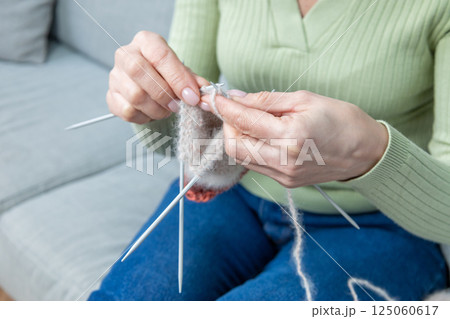 Woman spending time at home and knitting while sitting on the sofa 125060617