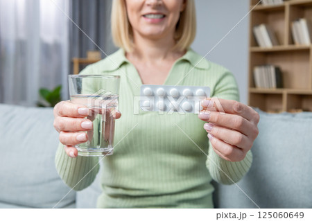 Blonde woman in her 50s taking hormone replacement pills Blonde woman in her 50s taking hormone replacement pills 125060649