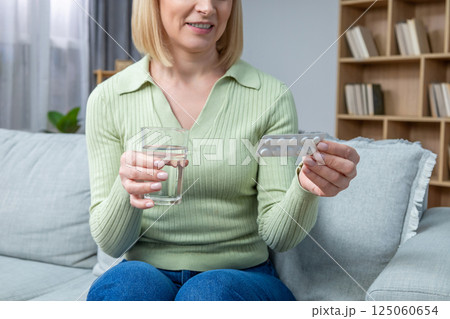 Blonde woman in her 50s taking hormone replacement pills 125060654