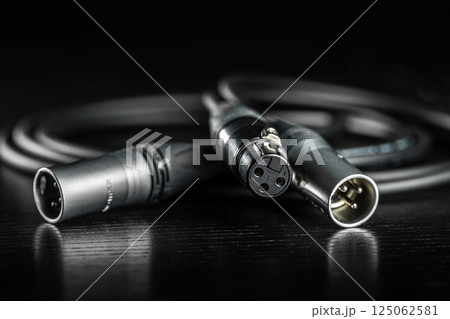 Xlr connectors and audio cable lying on a dark wooden surface Xlr connectors and audio cable lying on a dark wooden surface 125062581