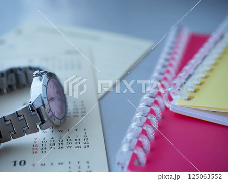 テーブルに置かれたカレンダーと手帳と腕時計 125063552