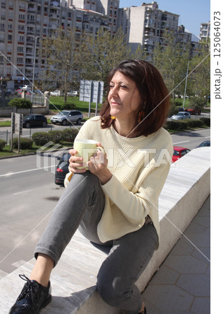 an adult woman on terrace making notes, working with phone an adult woman on terrace making notes, working with phone 125064073