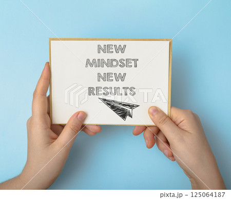 Hand holding a card with the words New Mindset, New Results written on it Hand holding a card with the words New Mindset, New Results written on it 125064187