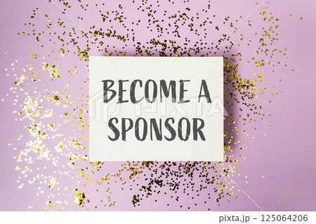 White sign with gold glitter on it that says Become a Sponsor 125064206
