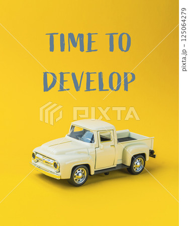 Toy truck is sitting on a yellow background with the words Time to Develop Toy truck is sitting on a yellow background with the words Time to Develop 125064279
