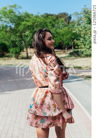 women in a summer dress with flowers walking in a spring park 125066725