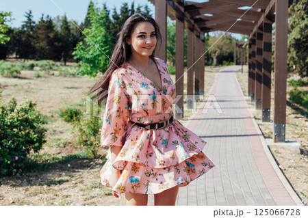 Brunette in a summer dress with flowers walking 125066728