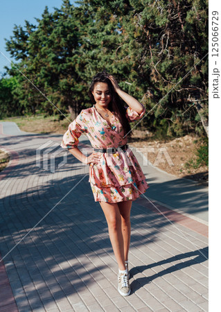 Brunette in a summer dress with flowers walking Brunette in a summer dress with flowers walking 125066729