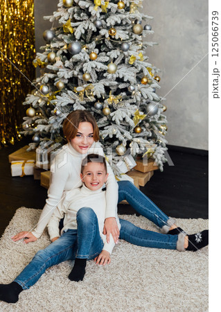 Mom and son decorating Christmas tree with toys with gifts for the new year Mom and son decorating Christmas tree with toys with gifts for the new year 125066739