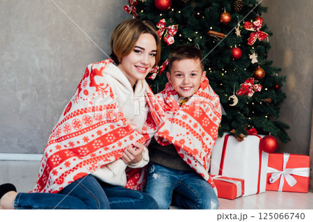 Mom and son decorating Christmas tree with toys with gifts 125066740