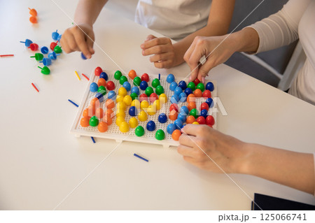 Female playing educational games with boy at table in classroom Female playing educational games with boy at table in classroom 125066741