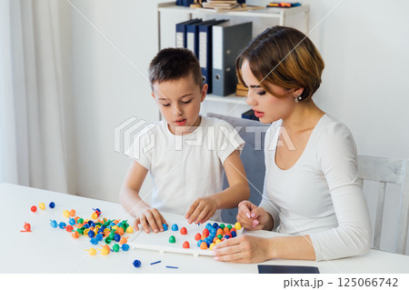 Female playing educational games with boy at table in classroom 125066742