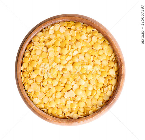 Yellow lentils in a wooden bowl. Dried seeds of a variety of Lens esculenta, a legume of small, round, and yellow in color fruits. High in protein and fiber, with soft and creamy texture, when cooked. 125067397