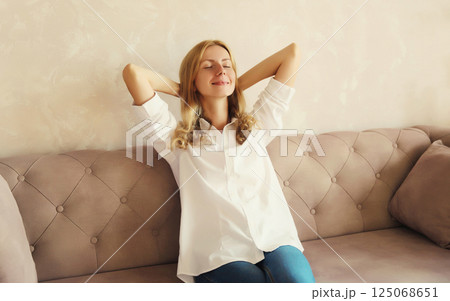 Happy relaxed young woman enjoying at home, satisfied girl sitting on the couch in living room Happy relaxed young woman enjoying at home, satisfied girl sitting on the couch in living room 125068651