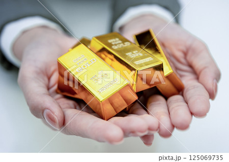 Asian woman holding gold bar in finance business. Asian woman holding gold bar in finance business. 125069735