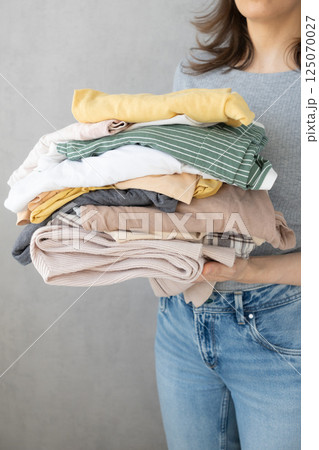 Laundry, woman holds stack of clothes in her hands after dry cleaning. housework, cleaning ironing.  125070027