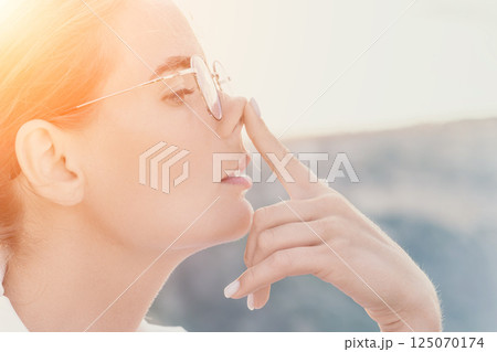 Woman summer travel sea. Happy tourist enjoy taking selfie photo outdoors for memories. Woman traveler posing on the beach at sea surrounded by volcanic mountains, sharing travel adventure journey 125070174
